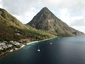 Scenic view of sea by mountains against sky