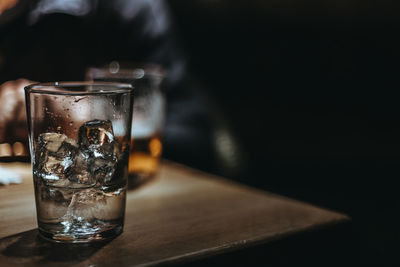 Close-up of ice cube in drinking glass on table