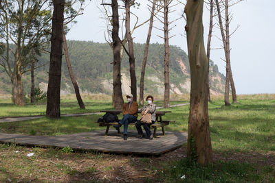 Aged caucasian couple 70-80 sitting in a recreational area with eucaliptus and pine trees. asturias