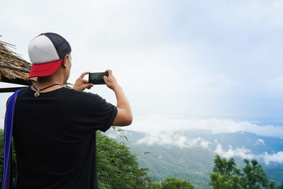 Rear view of woman photographing against sky