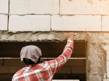 Rear view of man working on wall