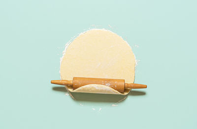 Home baking concept with raw dough rolled out with a rolling pin, isolated on green-mint background. 