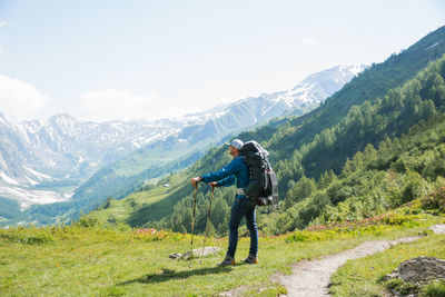 Full length of hiker standing on mountains against sky