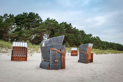 Hooded chairs on beach against sky