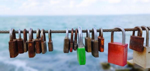 Close-up of padlocks on sea against sky