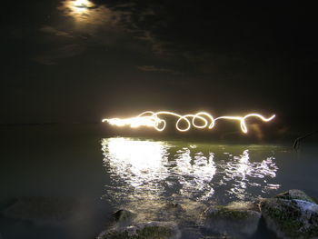View of illuminated lake against sky at night