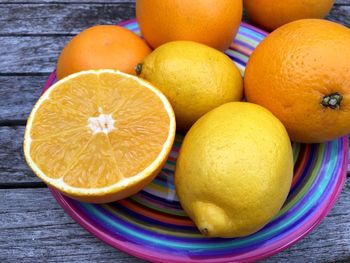 Close-up of halved and whole oranges in plate