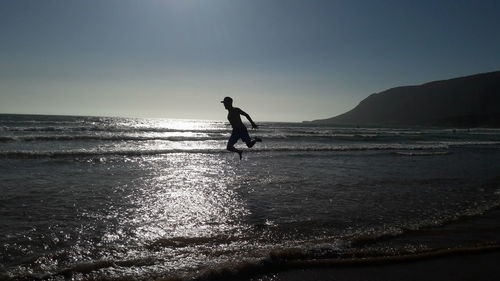 Silhouette man on beach against clear sky