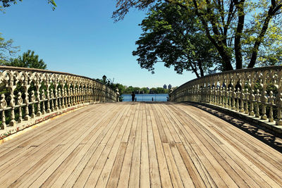 Empty footbridge against clear blue sky