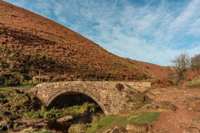Arch bridge on mountain against sky