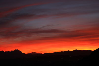 Scenic view of silhouette mountains against orange sky
