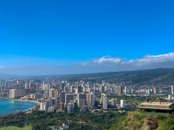 High angle view of buildings in city against blue sky