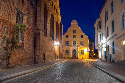 Street amidst buildings against sky at night