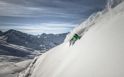 Man skiing on snowcapped mountain against sky