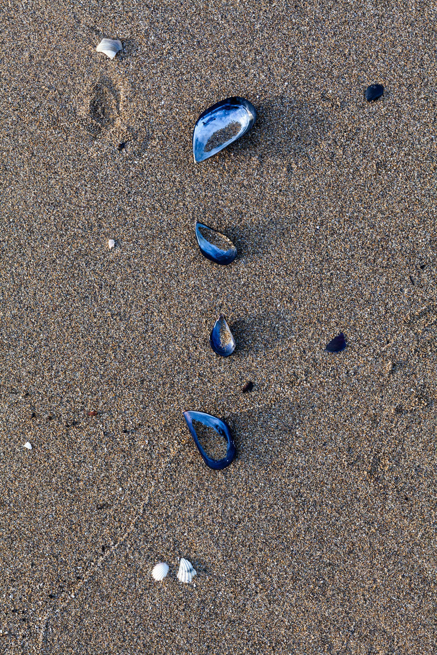 HIGH ANGLE VIEW OF PEBBLES ON SAND