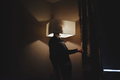 Rear view of man standing against wall at home