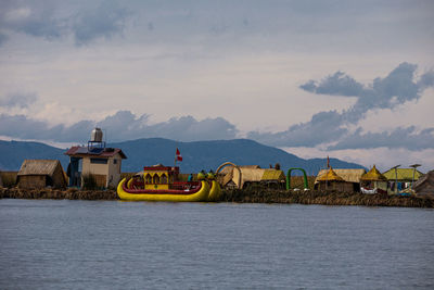 Nautical vessel on river by buildings against sky