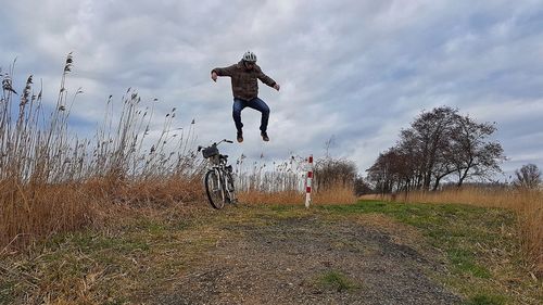 Man jumping on field against sky