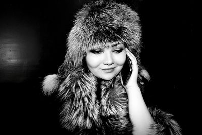 Portrait of smiling young woman against black background