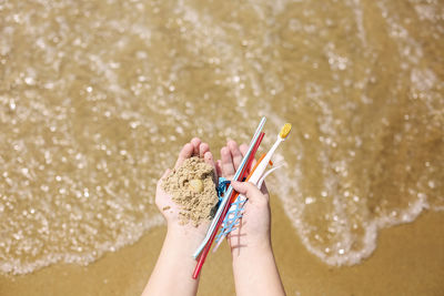 Midsection of woman holding umbrella on beach