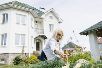 Senior woman gardening in front of house