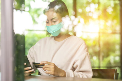 Young woman using credit card sitting at cafe