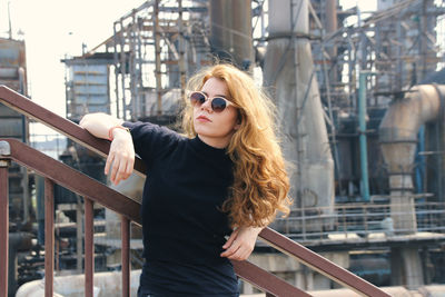 Portrait of woman standing by railing in city