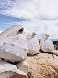 Stack of snail shel on rocks against sky