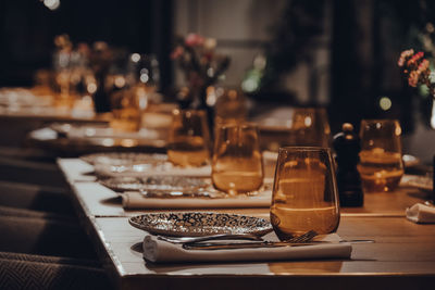 Row of tables set inside a restaurant, moody orange light, shallow focus.