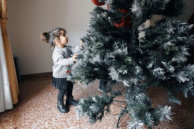 Grandparents decorate the christmas tree with their little granddaughter