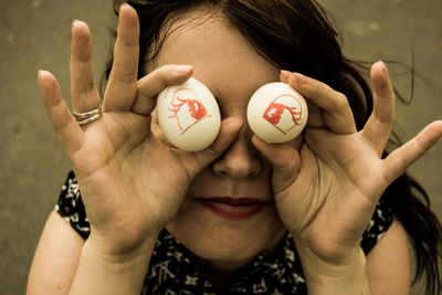 Close-up of smiling woman holding eyes drawn eggs