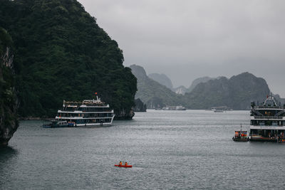 Boats in sea against mountain