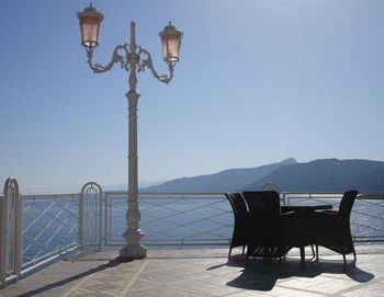 Empty chairs and tables against clear sky