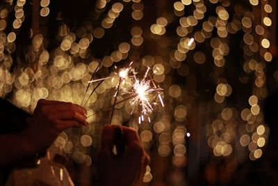 Close-up of hand holding illuminated lighting equipment at night