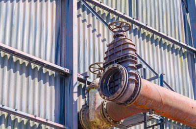 Low angle view of pipe attached to corrugated iron on factory