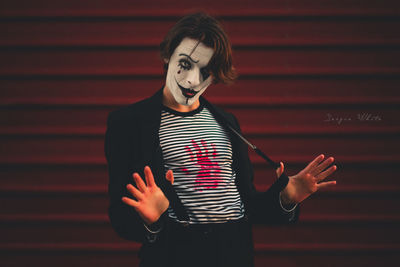 Young man standing against red wall