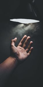 Close-up of hand holding paper over black background