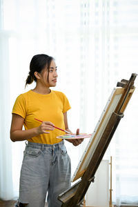 Side view of young woman using laptop at home