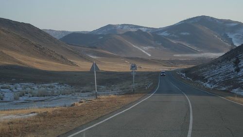 Empty road by mountains against sky