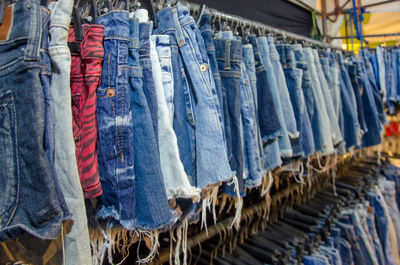 Close-up of denims hanging for sale at clothing store