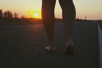 Low section of woman standing at sunset