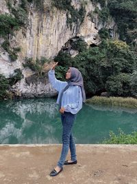 Young woman wearing headscarf standing against lake