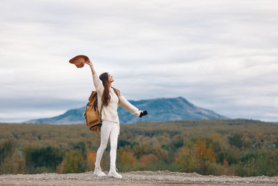 Full length of woman with arms raised standing on field