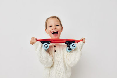 Portrait of smiling girl holding skateboard