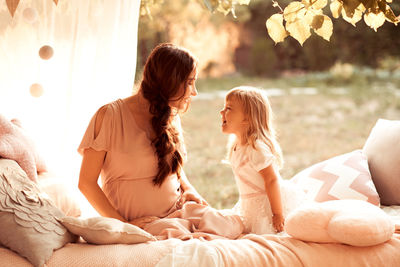 Mother and daughter sitting on bed at park