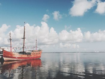 Boat in sea against cloudy sky