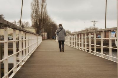 Rear view of man standing on footbridge