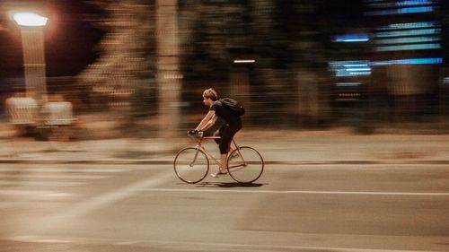 Side view of man riding bicycle on road