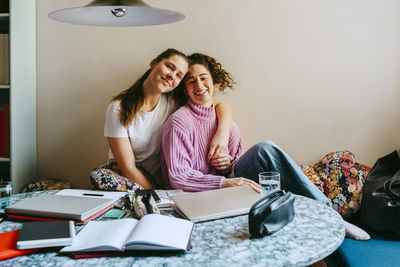 Portrait of happy young female friends sitting at home