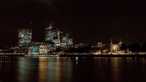 London illuminated buildings by river against sky at night